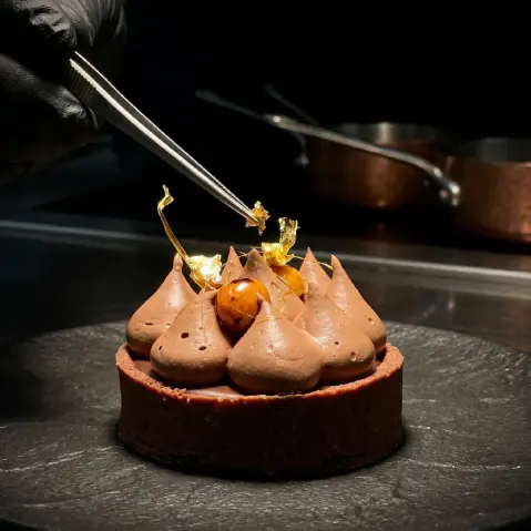 A plated dessert being finished with tweezers.